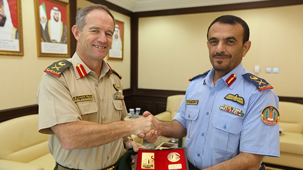 Major General Mike Hindmarsh at the National Defense College shakes hands while presented with something by another man
