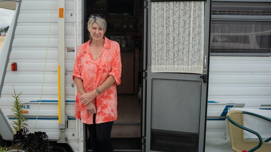 A woman stands in front of a caravan