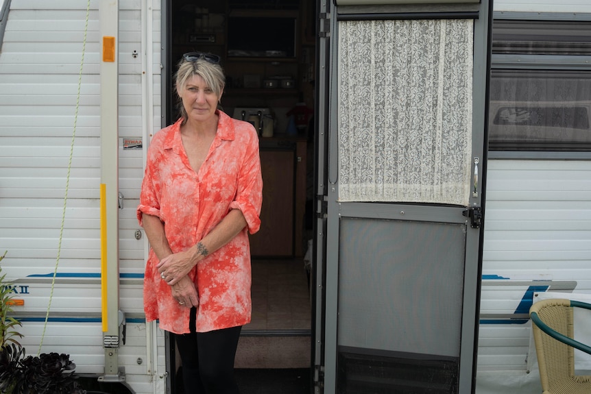 A woman stands in front of a caravan