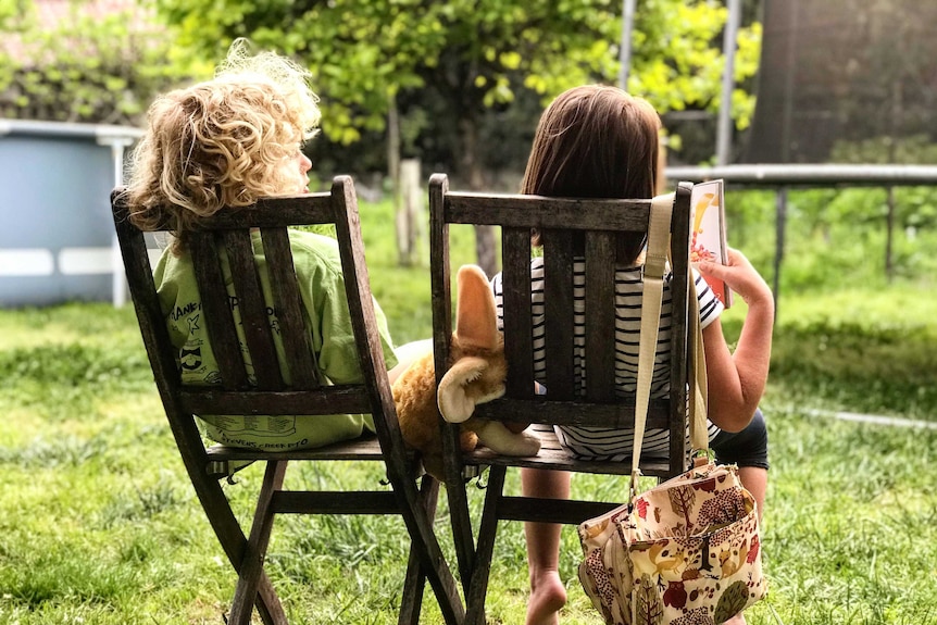 Two small kids sitting on camp chairs with their backs to the camera