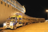 A ship is loaded with live cattle at night.