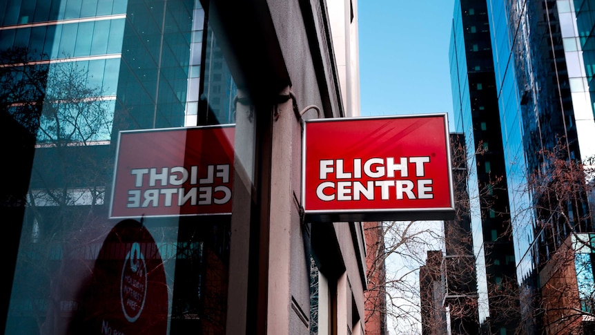 A red and white Flight Centre sign in the foreground, with the Melbourne CBD skyline in the back.