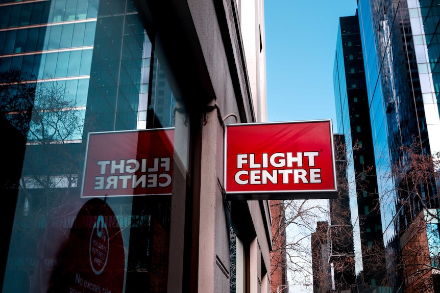 A red and white Flight Centre sign in the foreground, with the Melbourne CBD skyline in the back.