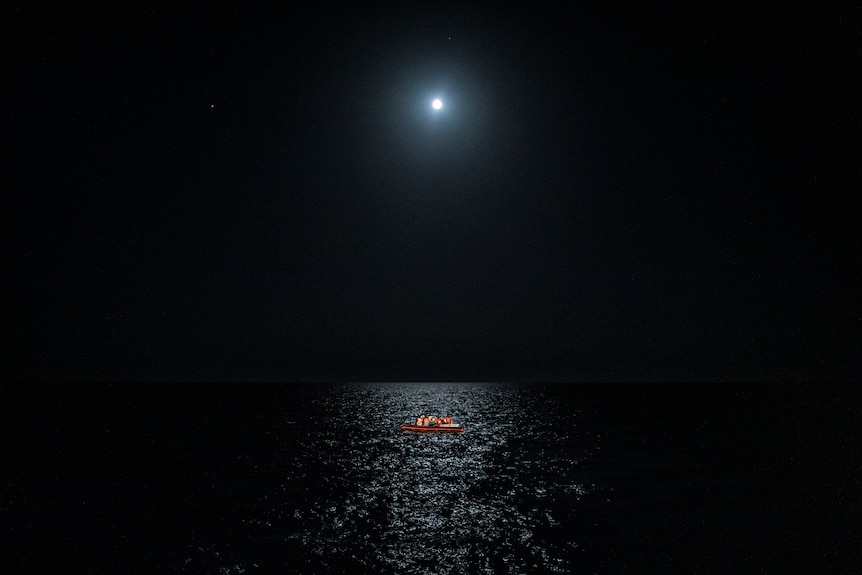 The moon reflects on a black sea.