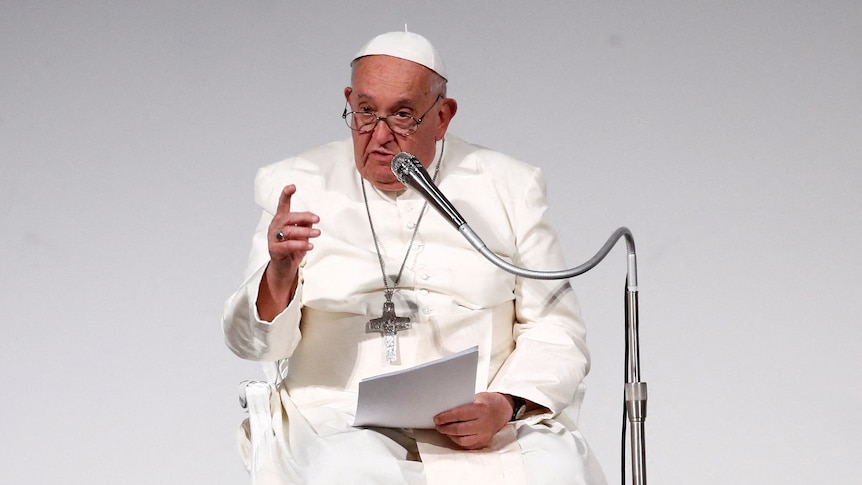 The pope speaks into a silver-coloured microphone.