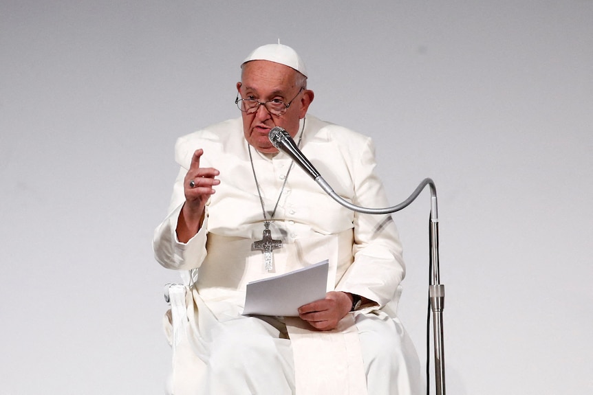 The pope speaks into a silver-coloured microphone.