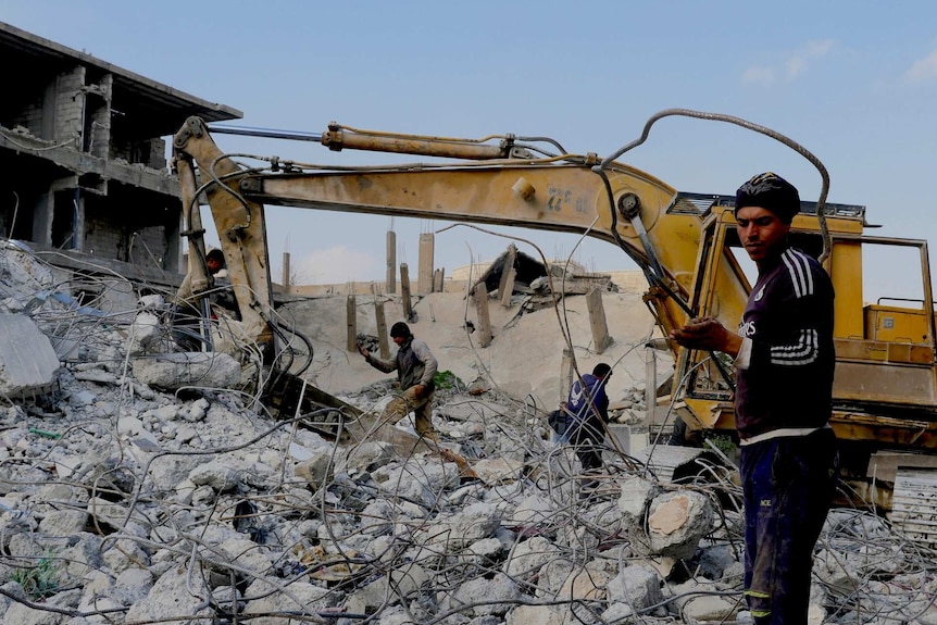 Men work with a bulldozer to clear rubble