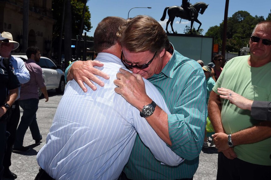 Cole Miller's father is comforted by a friend during the rally.