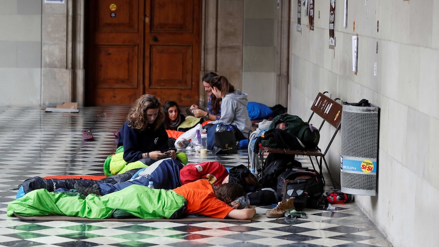 People wake up after spending the night inside the University of Barcelona. They are in sleeping bags.