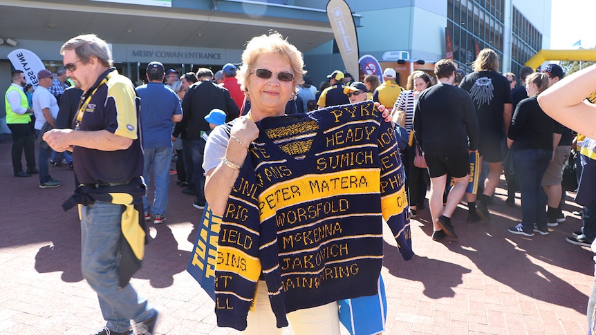 Margherita Thornton holds up a jumper decorated with the names of West Coast Eagles players.