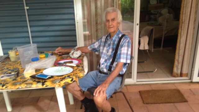 An old man sits at a dinner table.