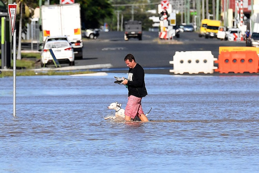 A man and his dog walk through floodwaters in Rockhampton in central Queensland on April 7, 2017