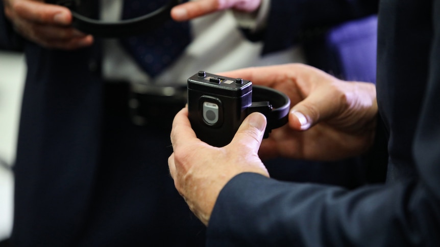 A small black square device being held by a persons hands