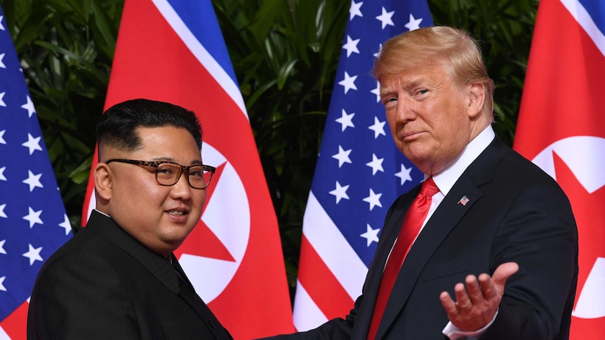 Donald Trump gestures to the camera and smiles as he meets Kim Jong-un.