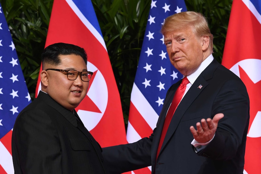 Donald Trump gestures to the camera and smiles as he meets Kim Jong-un.