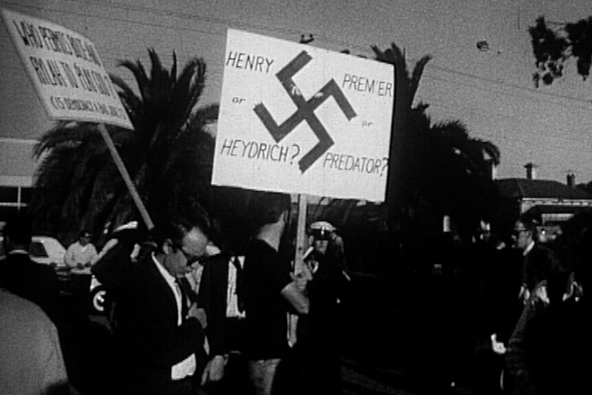 A black-and-white historical image of Victorian anti-capital punishment protesters, with a sign comparing the Premier to Hitler