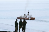 Three men watch the US Coast Guard plunge through ice.