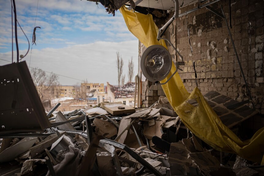 an operating light hangs from the ceiling of a destroyed section of a hospital in Izium