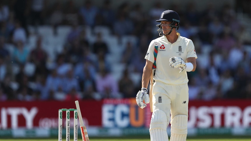 England batsman Joe Denly walks away from the pitch with his bat under his arm. Another bat rests on the stumps.