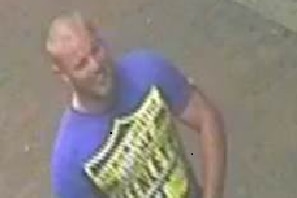 A CCTV shot of a burly bald man in a blue shirt