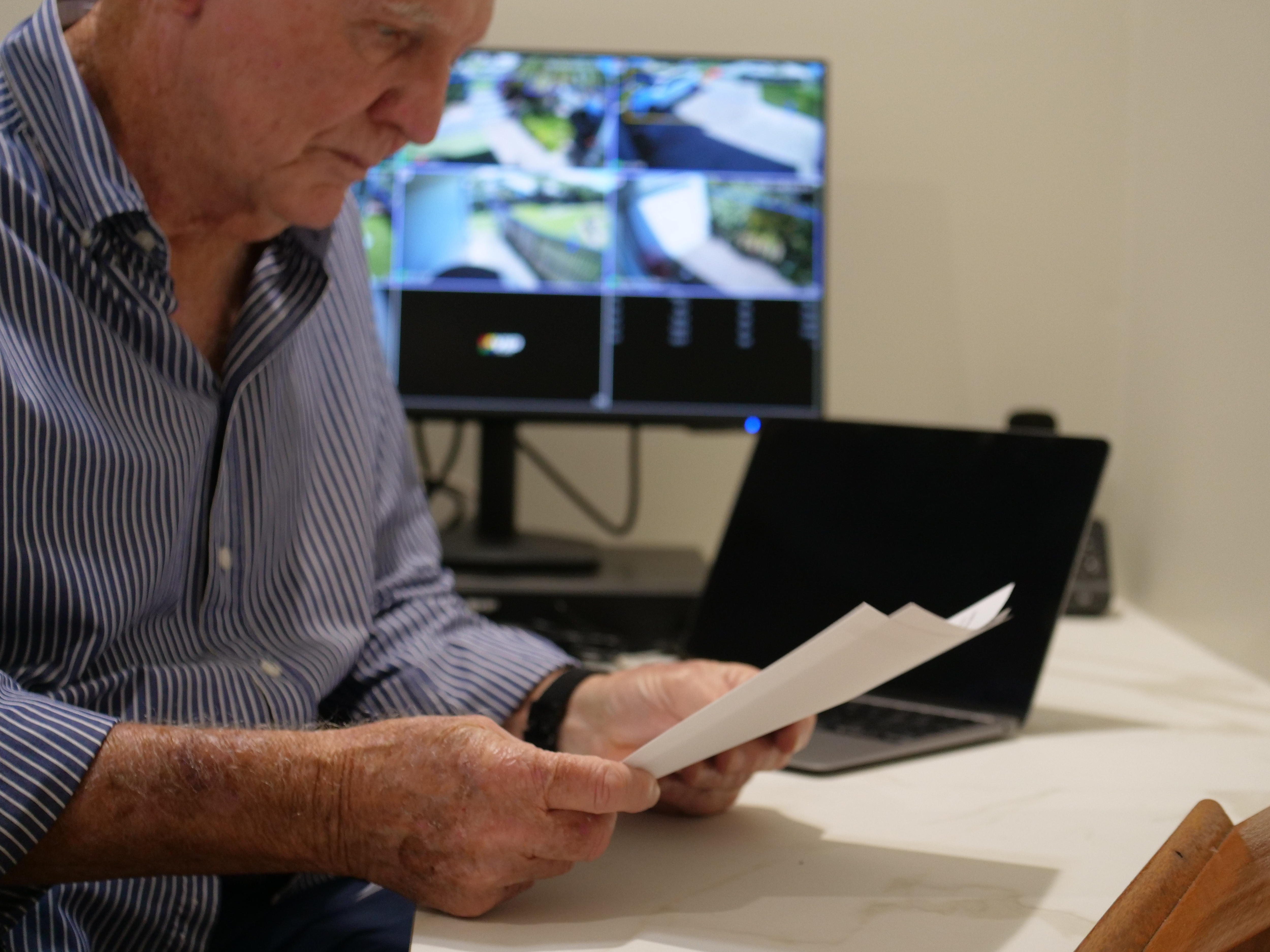 An older man sitting at a desk, looking at papers