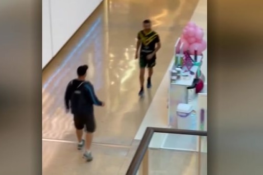 A man confronts another man who holds a knife in a shopping centre.