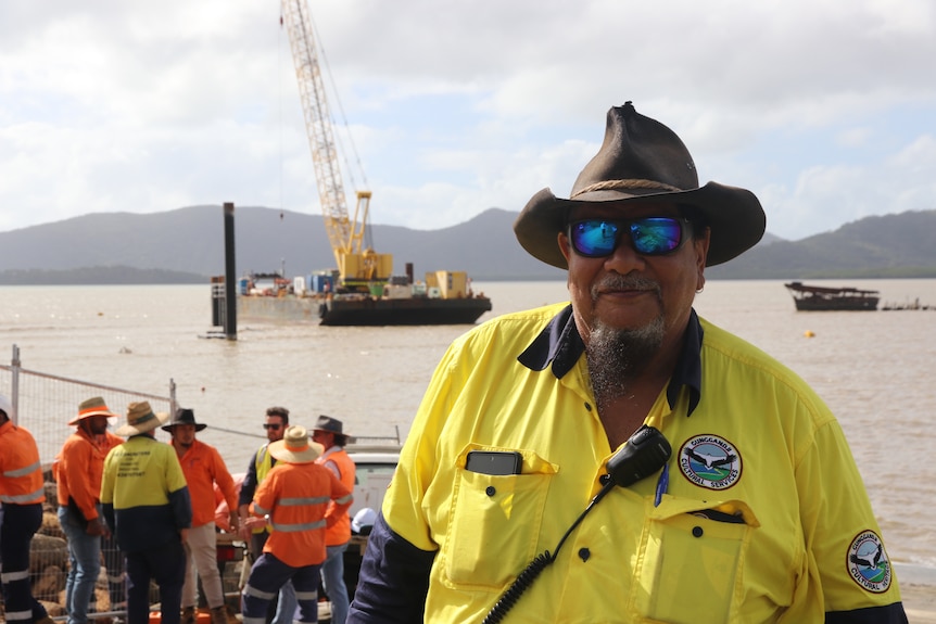 A man in work clothes with a hat and sunglasses