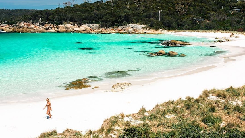 Woman walking on beach at Bay of Fires, Tasmania