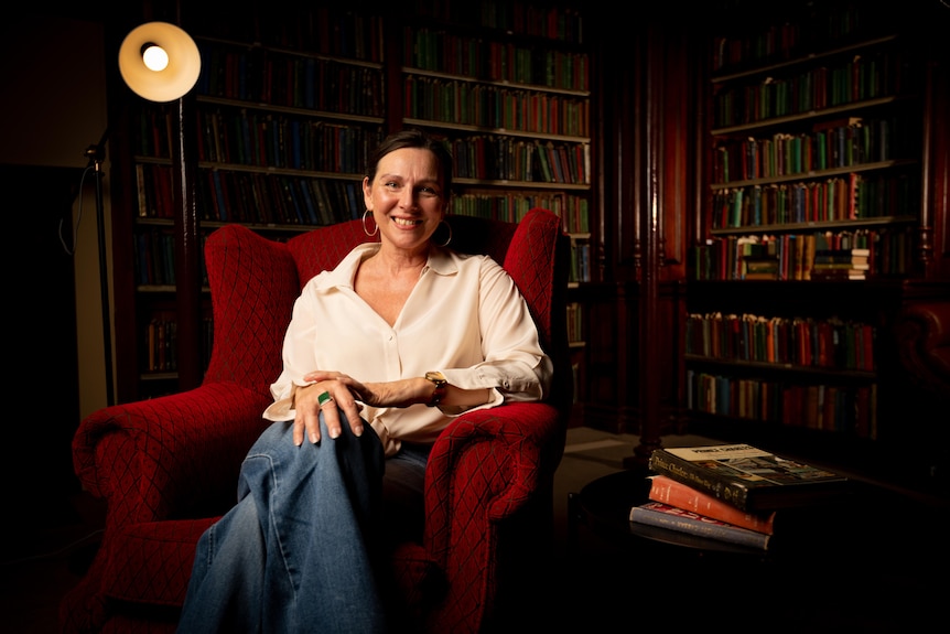 A woman sits on an armchair and smiles.