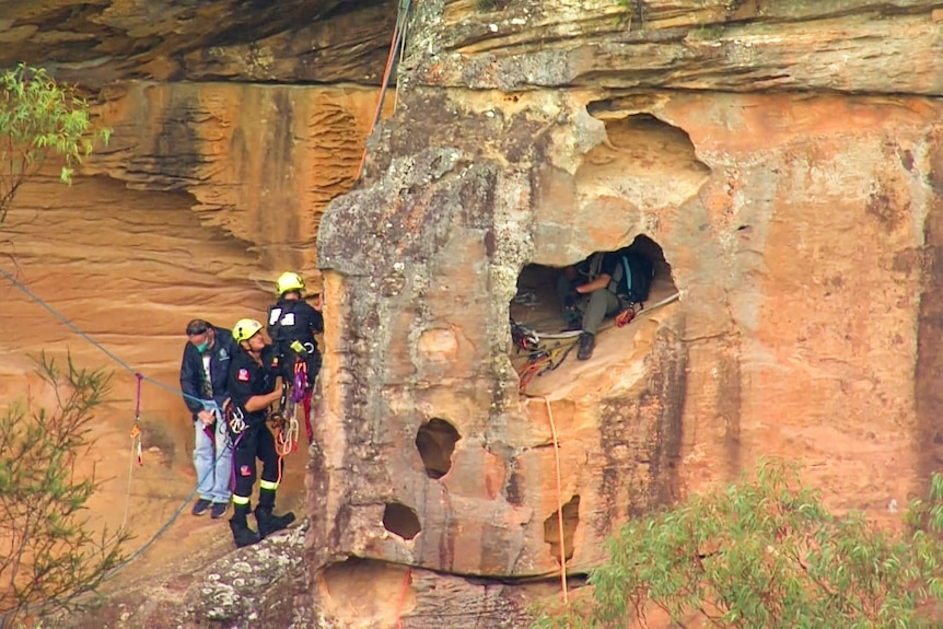 three rescue officers on the side of a cliff