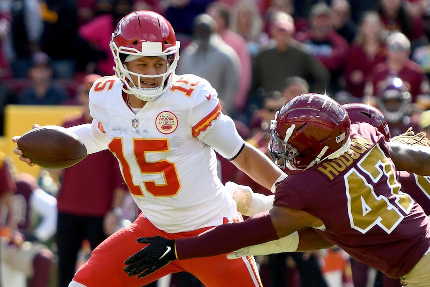 Patrick Mahomes fends off a would-be tackler while running with the ball