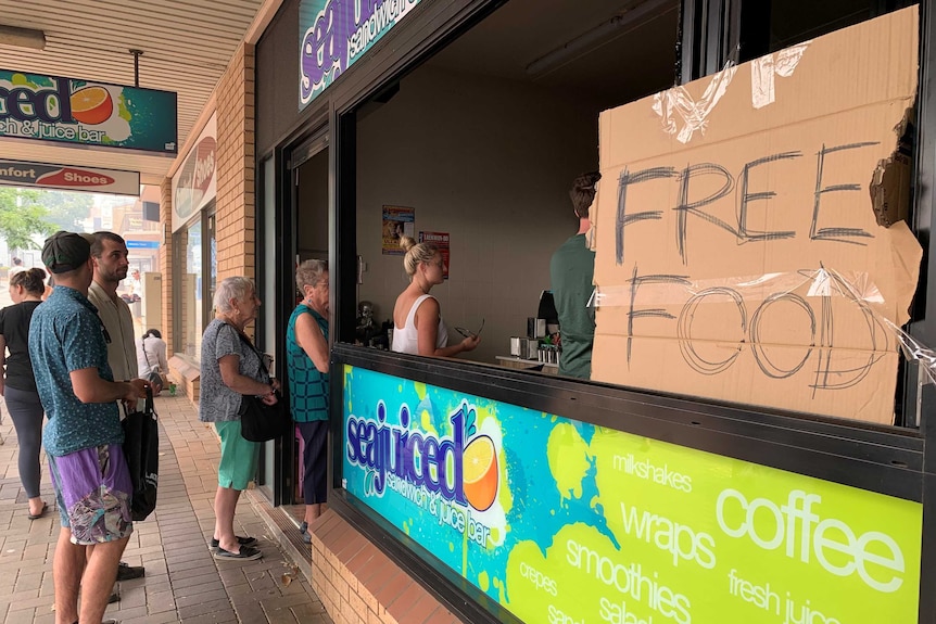 A cafe with a queue and a free food sign