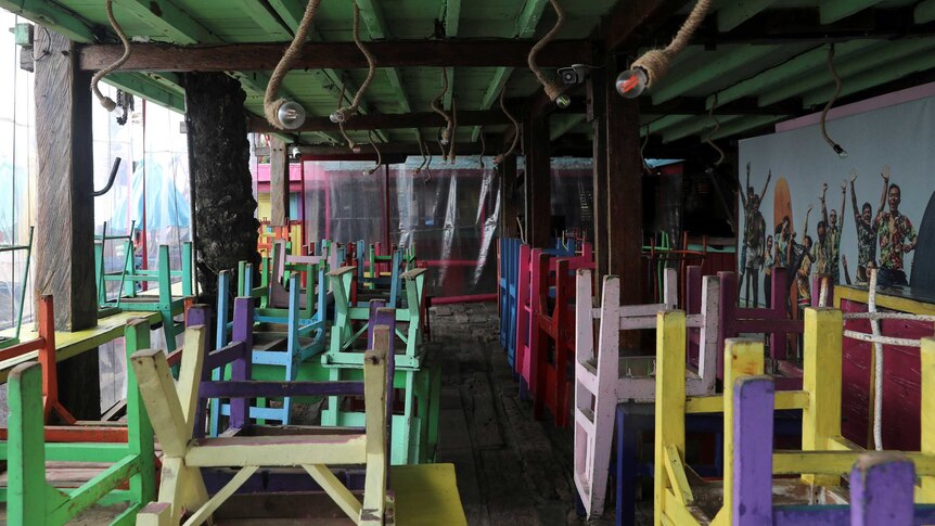 A series of colourful upturned chairs in an empty restaurant by the beach in Bali.