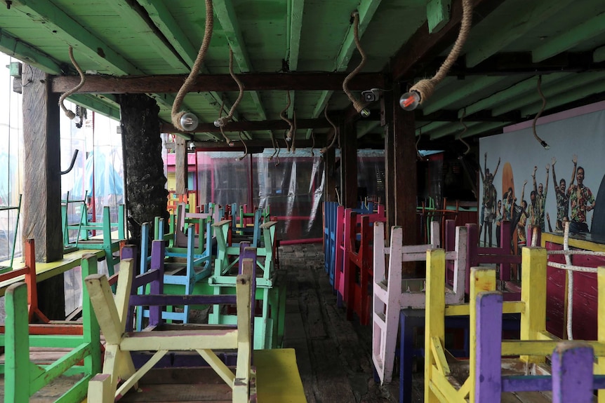 A series of colourful upturned chairs in an empty restaurant by the beach in Bali.