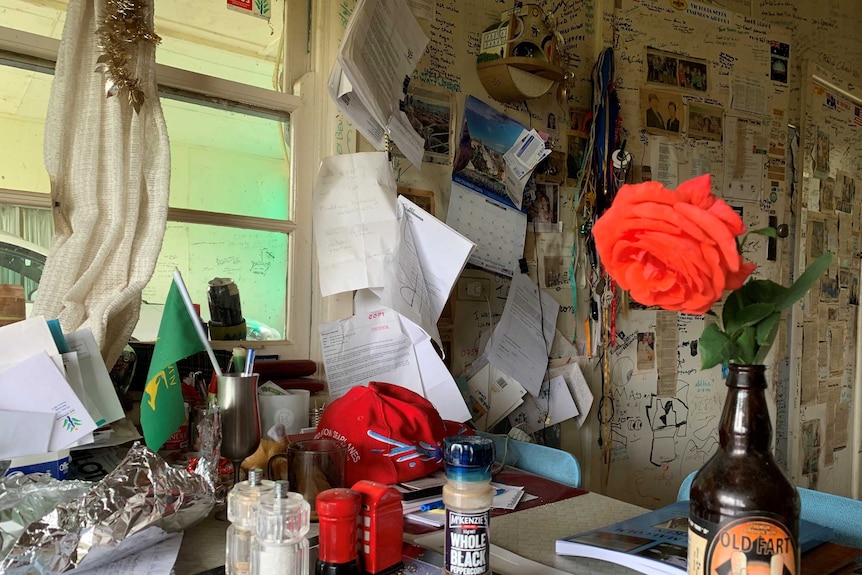 Ben Buckley's kitchen table, covered in books, a flag, notes and a wall lined with with notes and pictures.