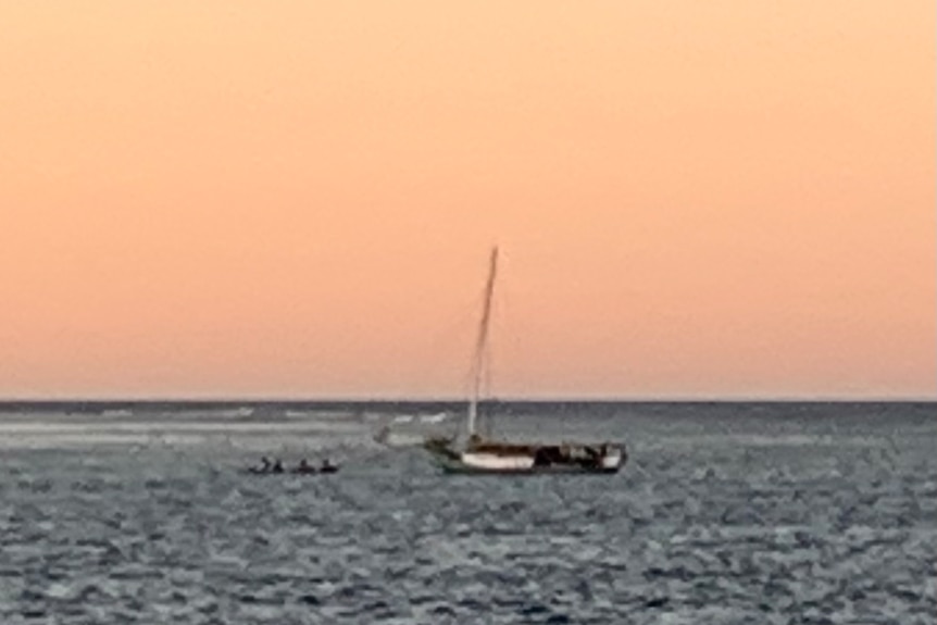 A boat sits on the water at sunset