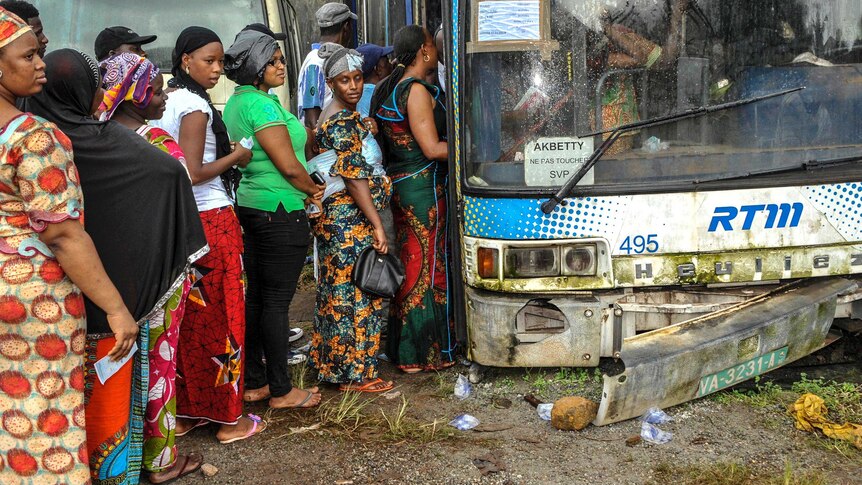 Voters in Guinea queue to vote for the presidential elections at a polling booth in a run-down bus.