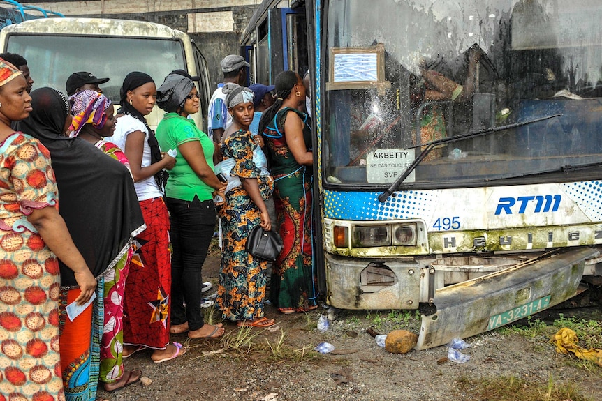 Voters in Guinea queue to vote for the presidential elections at a polling booth in a run-down bus.