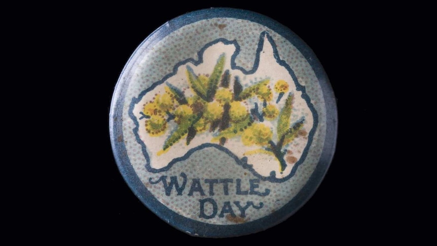 A circular badge with a painting of yellow flowers in an outline of Australia with Wattle Day written underneath