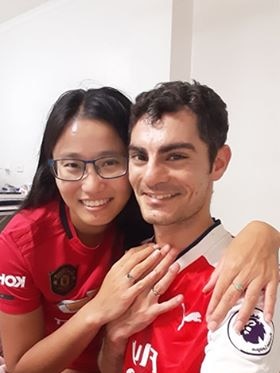 Damoon and Meg, one in an arsenal jersey and the other in a Manchester United Jersey wearing engagement rings.