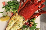 A luscious-looking plate of lobster with some greens and lemons.