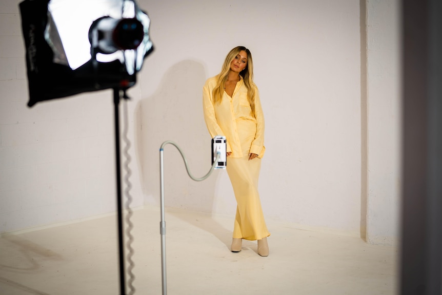 An influencer stands in front of a camera in a studio to shoot a picture
