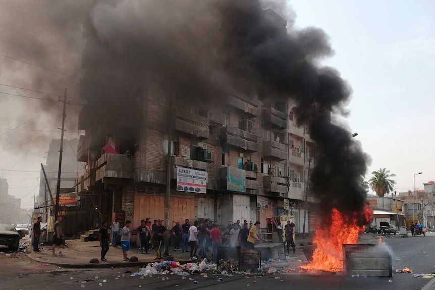 Anti-government protesters set a fire, empty trash into the streets and block roads in Baghdad.