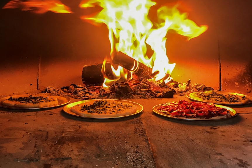 Pizzas being cooked in a wood-fired oven.