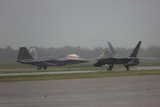 Two US Air Force F-22 Aircraft sit on an airstrip in the rain