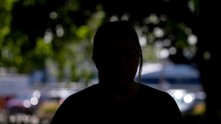 The silhouette of a woman in front of a tree.