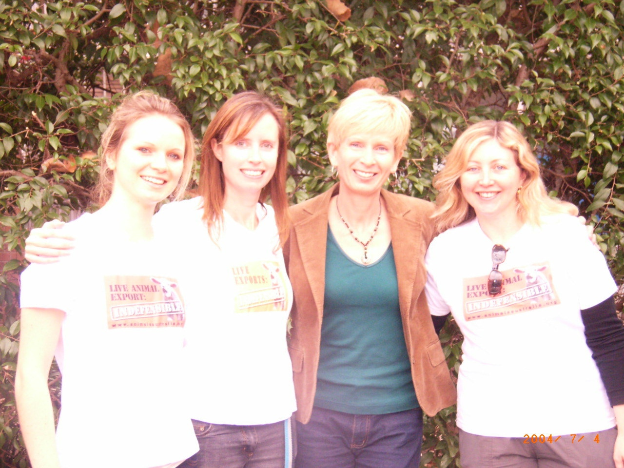 Four women stand together, smiling.