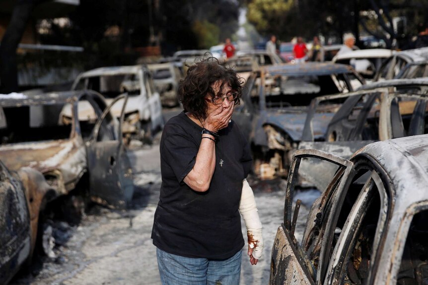 A woman reacts as she tries to find her dog, following a wildfire at the village of Mati.