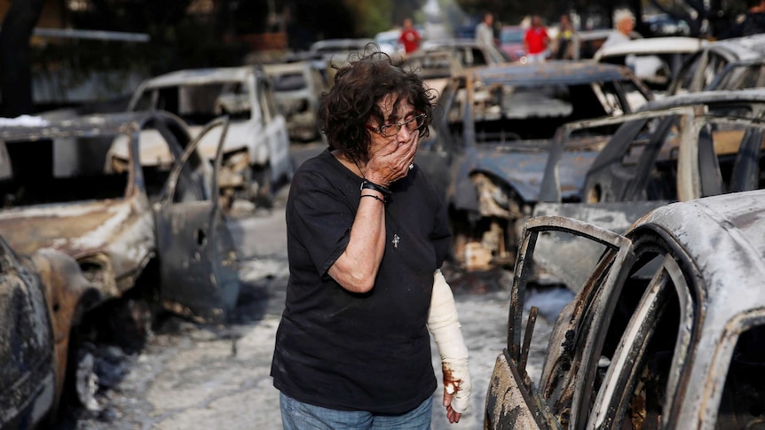 A woman reacts as she tries to find her dog, following a wildfire at the village of Mati.