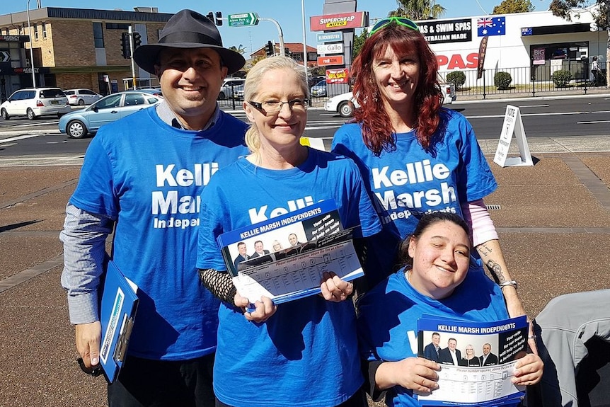 Four people in blue shirts, including independent councillor Kellie Marsh, smile in the street. 